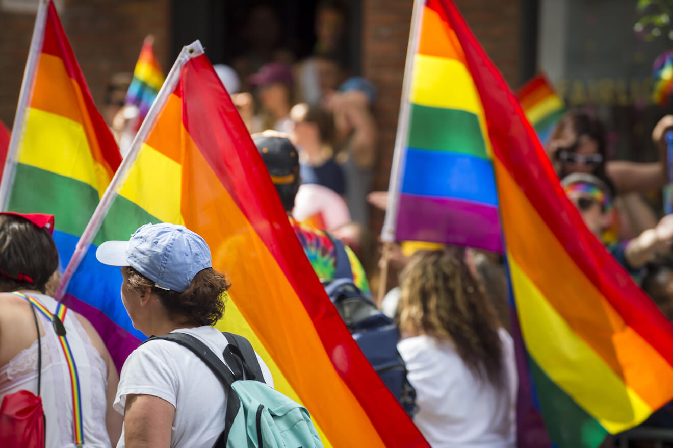 People marching in gay pride parade with rainbow flags