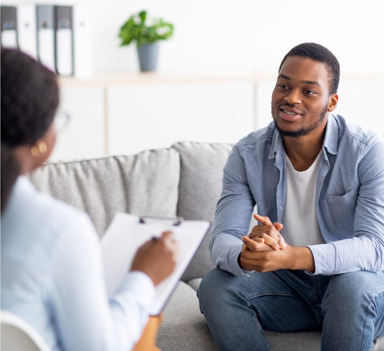 Man sitting on couch across from a woman with a sheet of paper