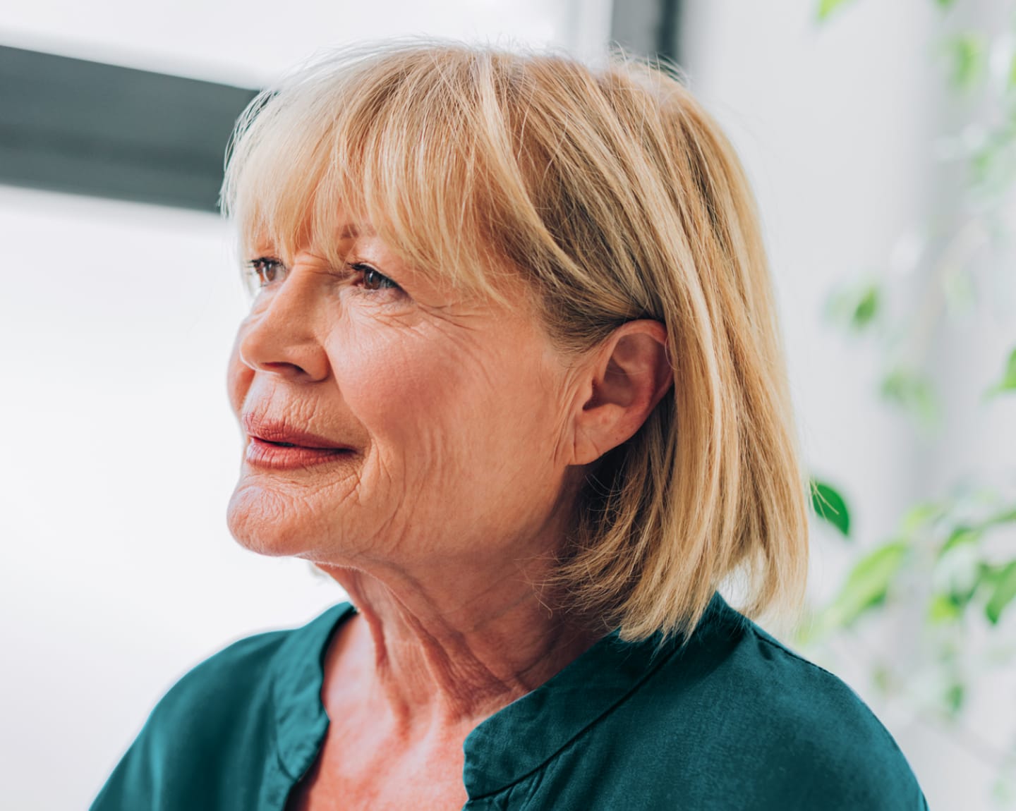 A senior woman with blonde hair smiling and looking off in the distance