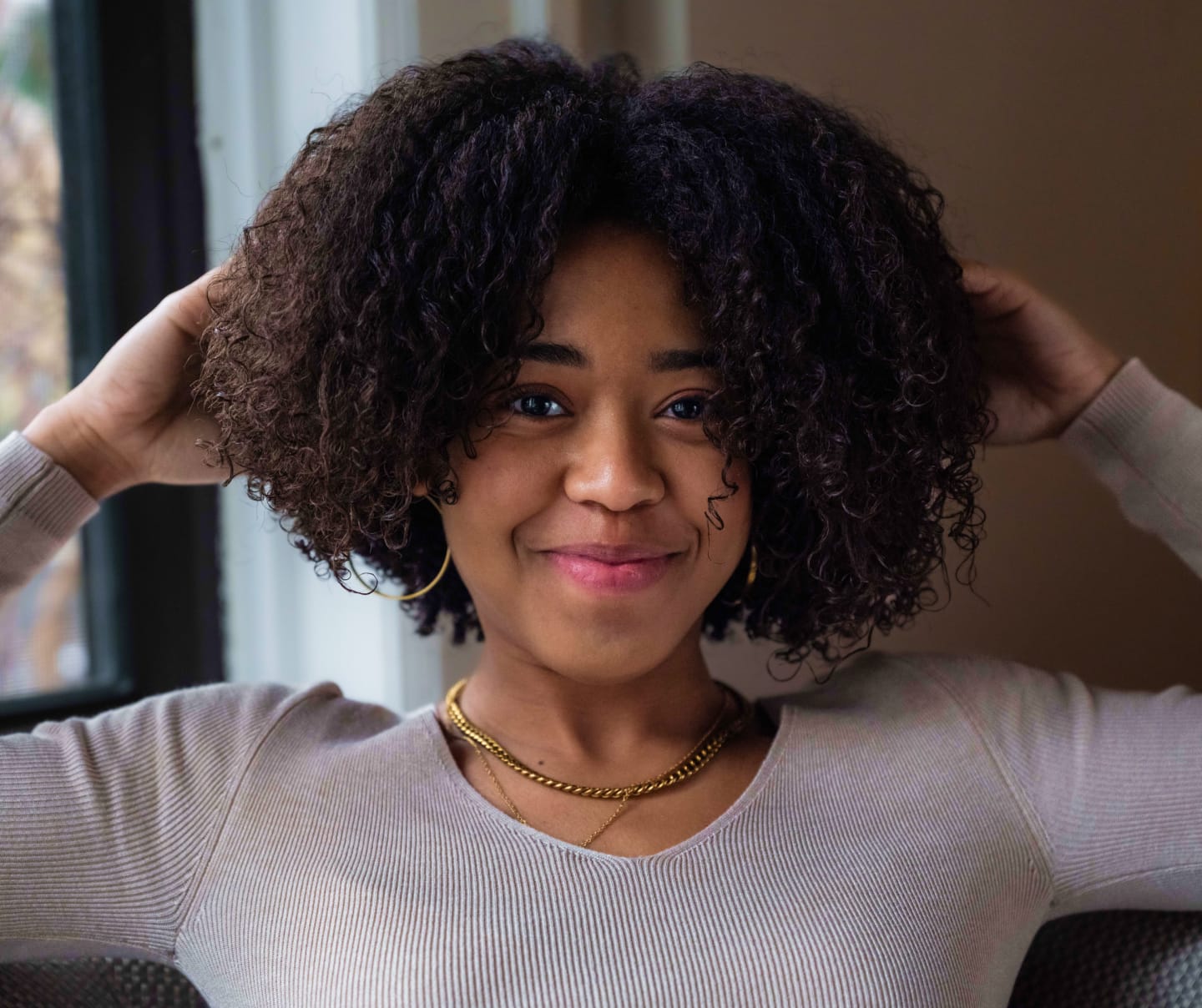 Woman holding her arms up and touching her hair