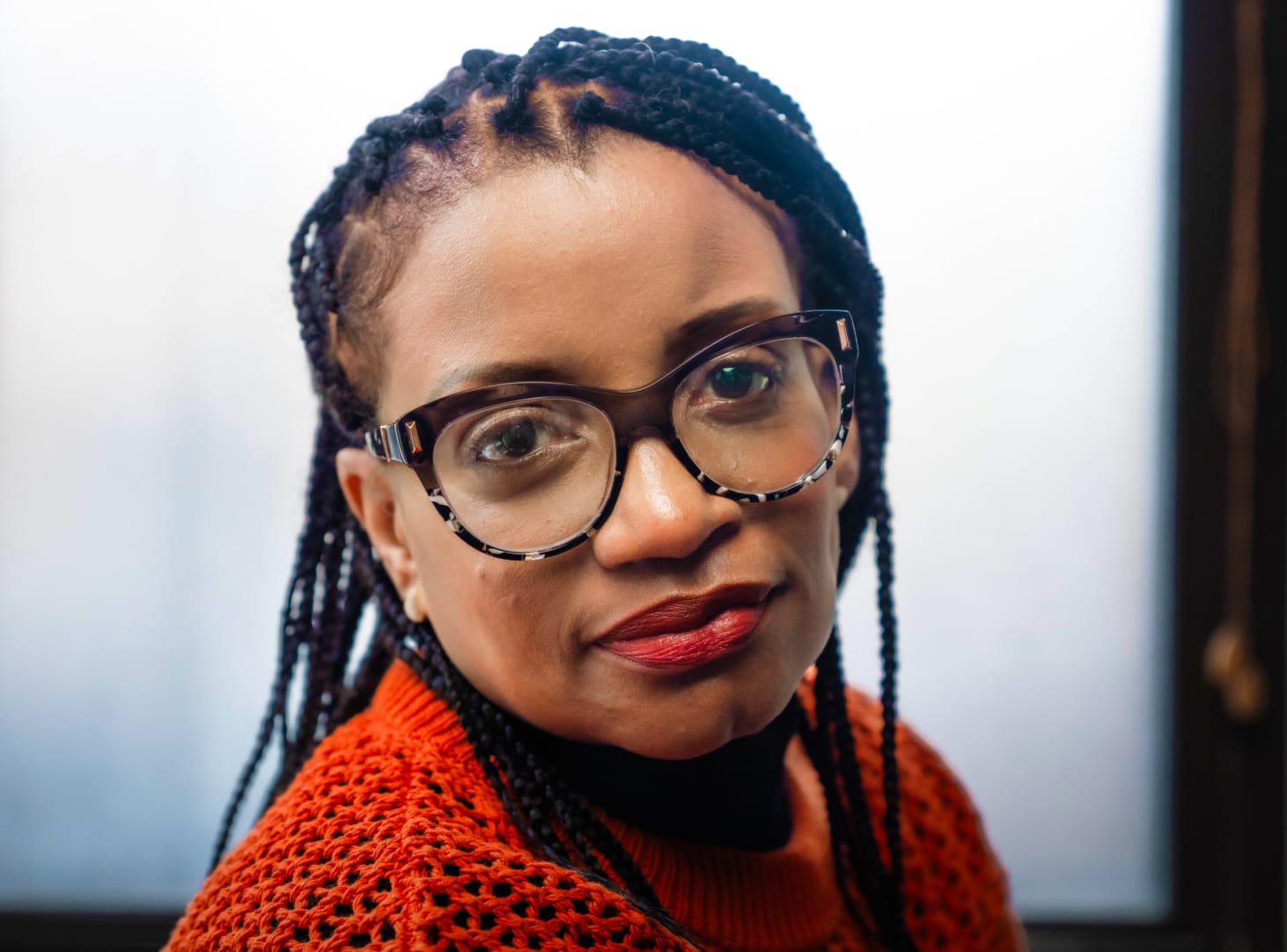 Woman with glasses and a red sweater looking hopeful