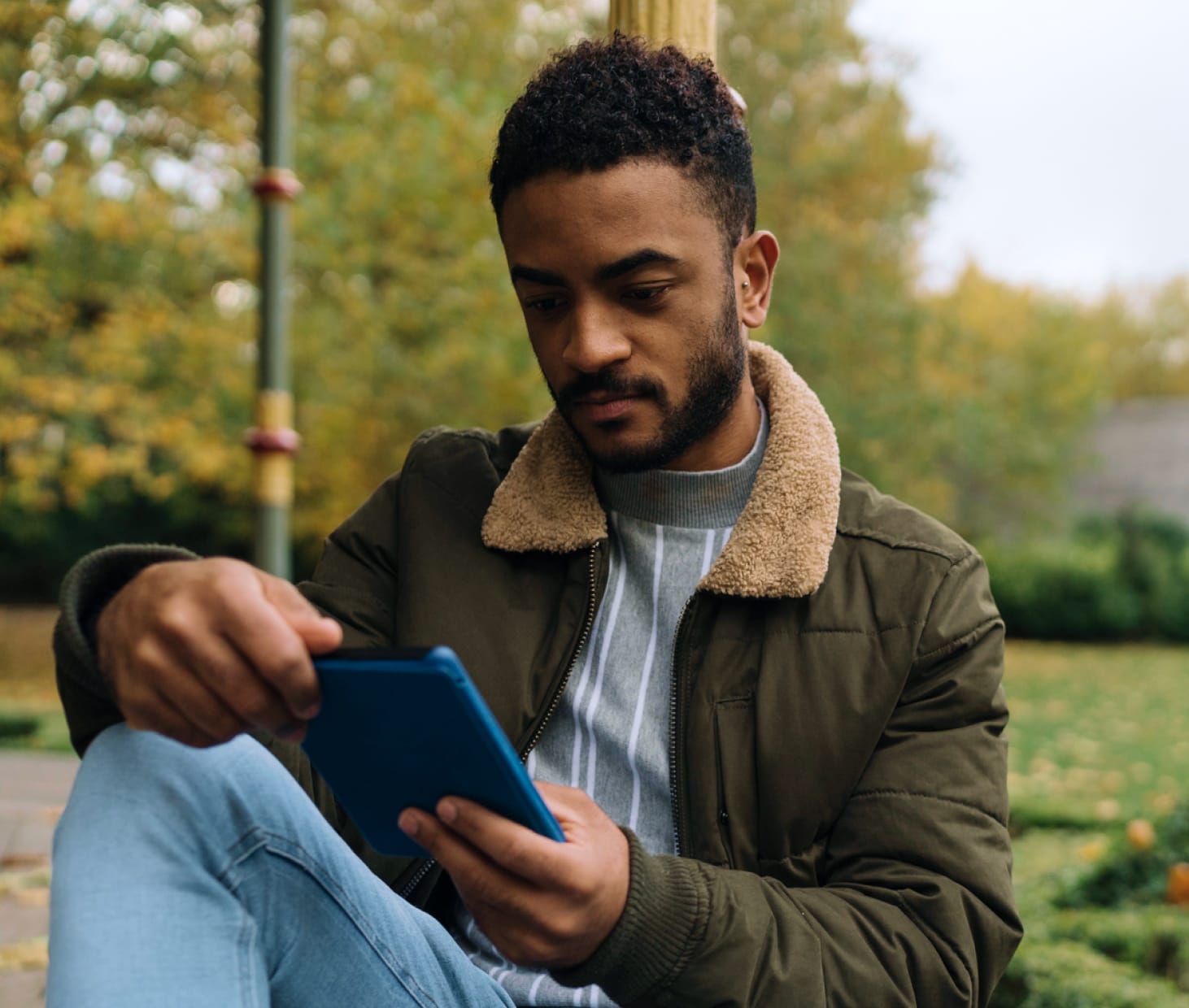 Photo of a man sitting on a park bench looking at his phone