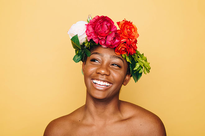 A smiling woman wears a crown of flowers