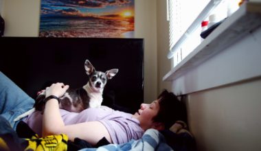 Depressed lady with a dog lying down on a mattress on the floor.