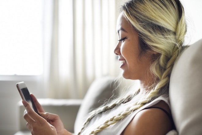 A woman is happy while n her mobile device