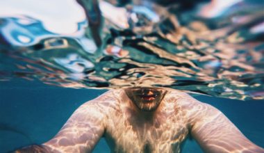 man half under water holding camera