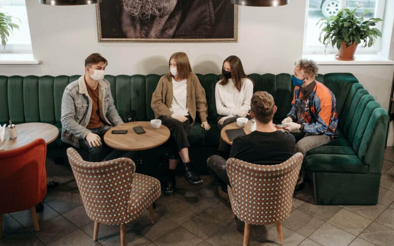 group of people sitting wearing masks