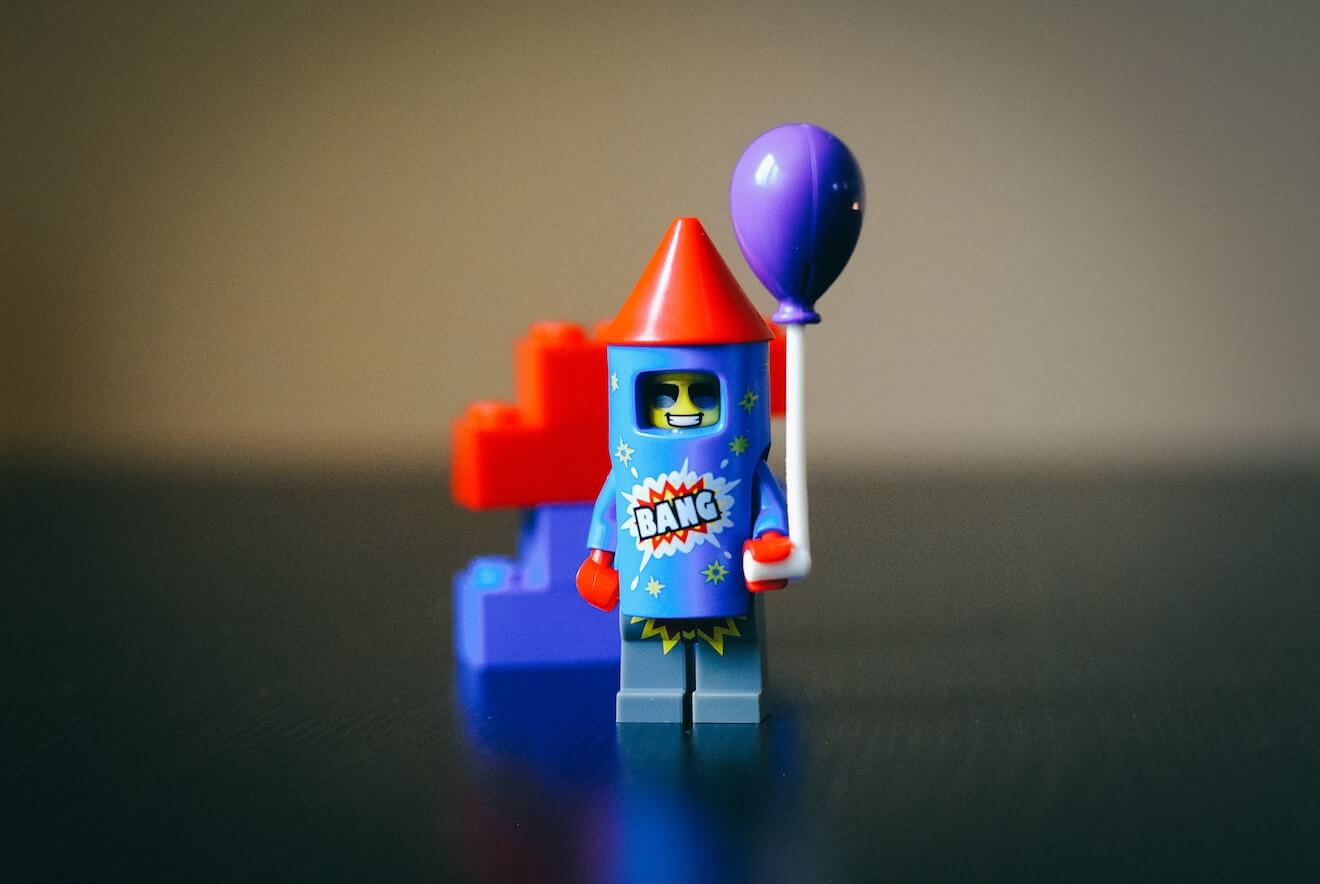 A Lego rocketman holding a balloon