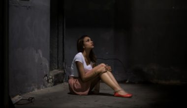 woman sitting in dark alley