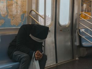 Man in black hoodie riding the subway