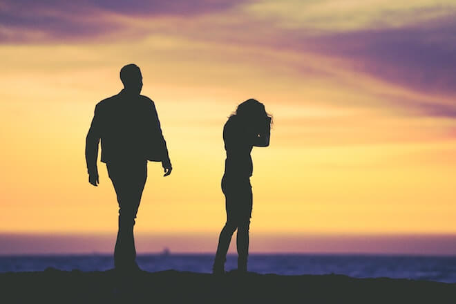 A man and a woman are silhouetted in front of a sunset