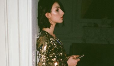 woman in gold dress leaning on doorframe