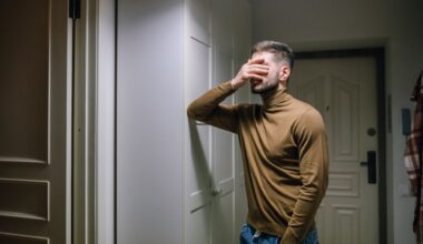 man in brown shirt standing with hands over face