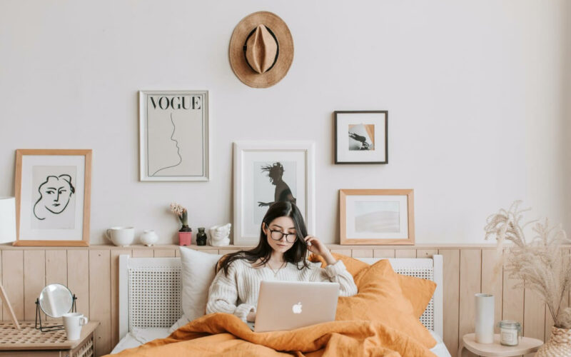 woman lying in bed on computer