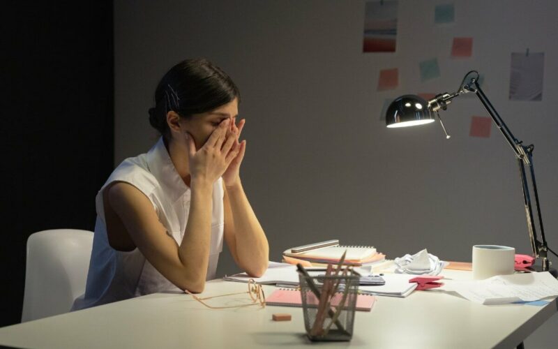 woman sitting at desk with head in hands