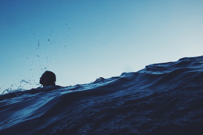 A woman swims in the sea at dusk