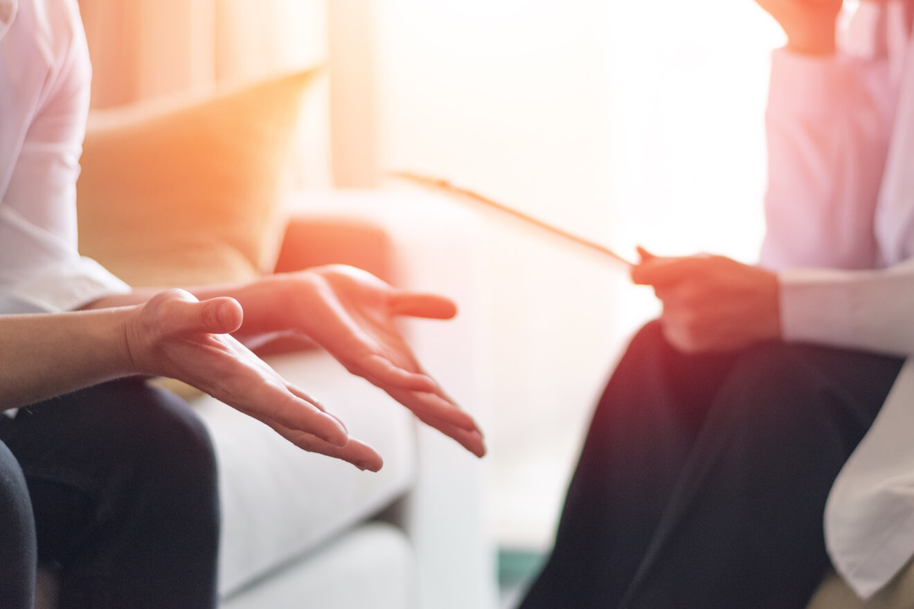 Woman on couch with hands open, talking to a therapist