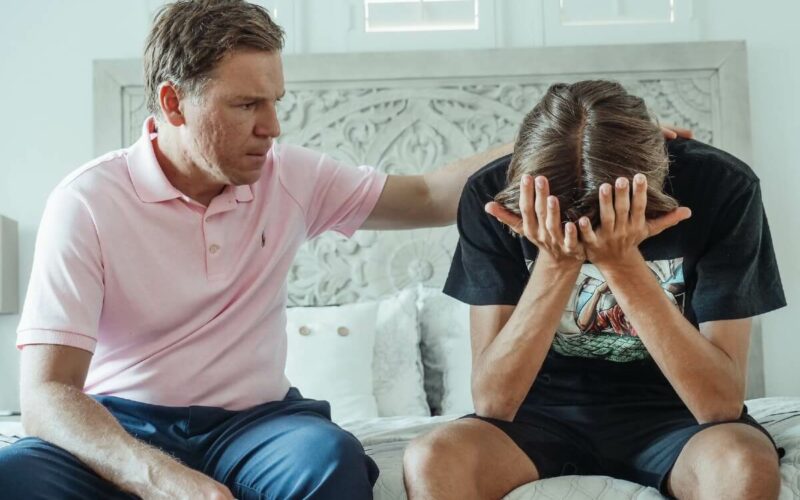 father putting his arm on son's back