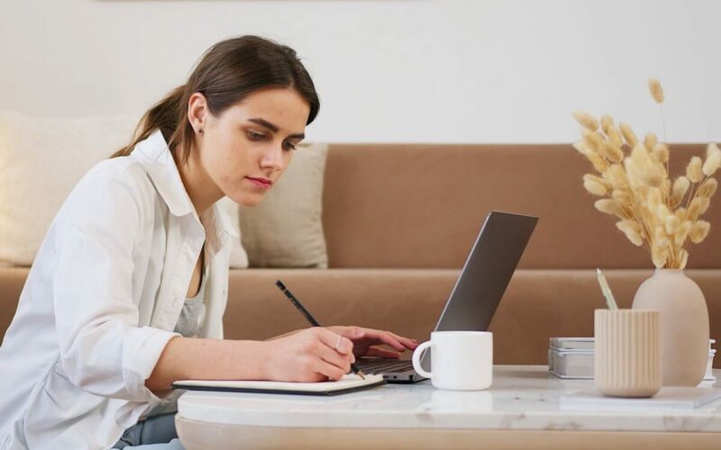 woman searching on computer and taking notes