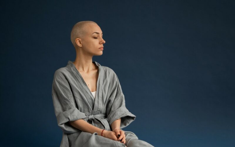 woman with shaved head sitting with eyes closed