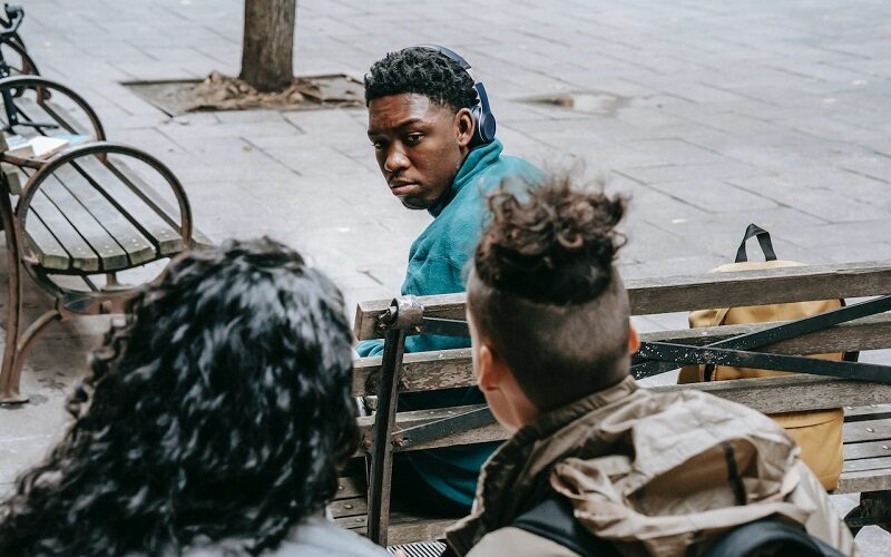 Faceless friends bullying black classmate on bench