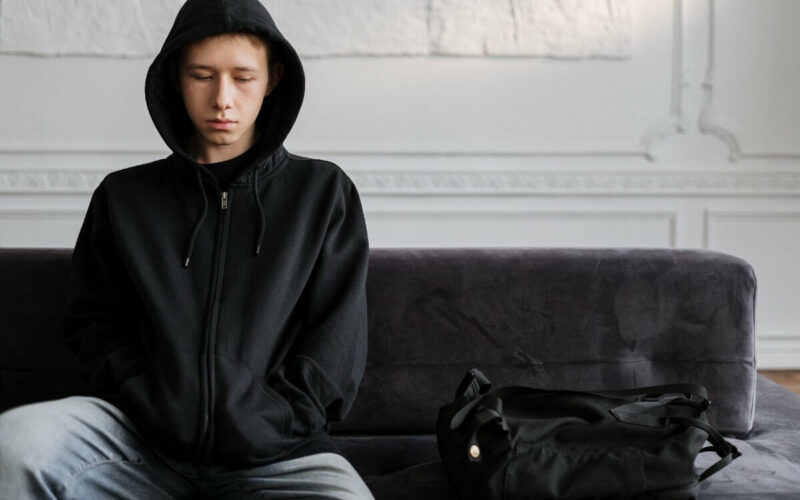 male teenager sitting on couch looking sad