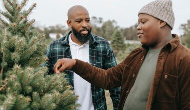 Smiling black dad talking to son touching needles of spruce