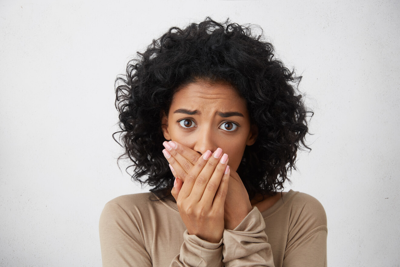 Woman covering her mouth with fearful eyes