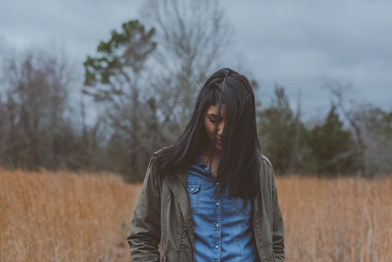 Young woman gazing downward in a field