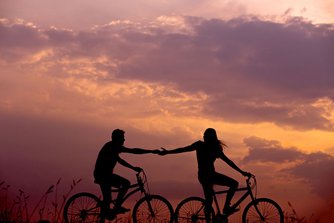 Couple riding bikes at sunset