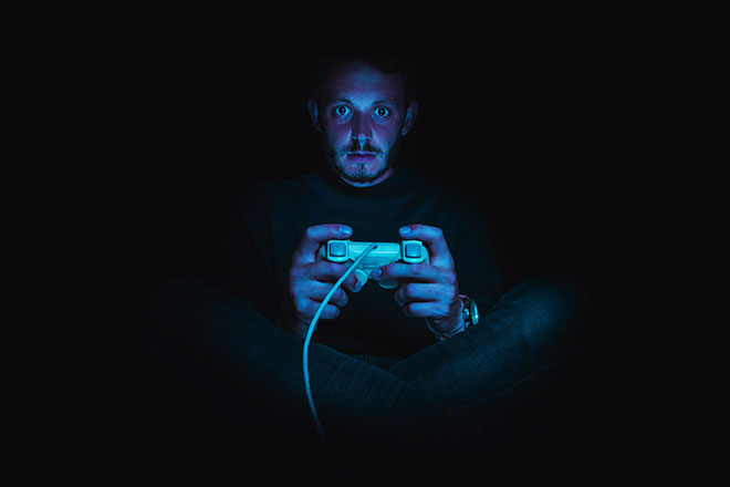 A man sits in the dark playing video games