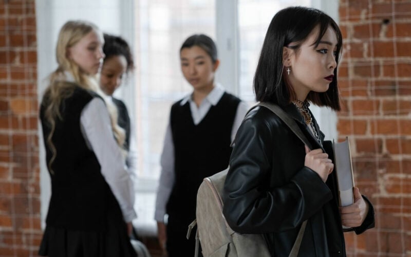 Woman in leather jacket being stared at by three classmates