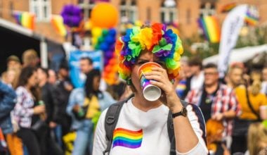 person dressed in pride colors drinking