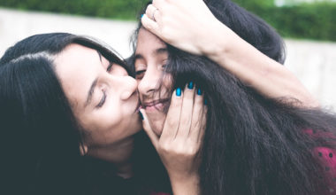 mother kissing daughter's face