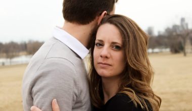 woman embracing male partner staring blankly toward camera