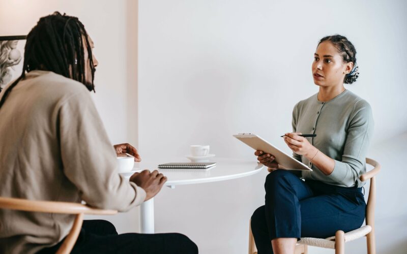 woman taking notes speaking to man across from her