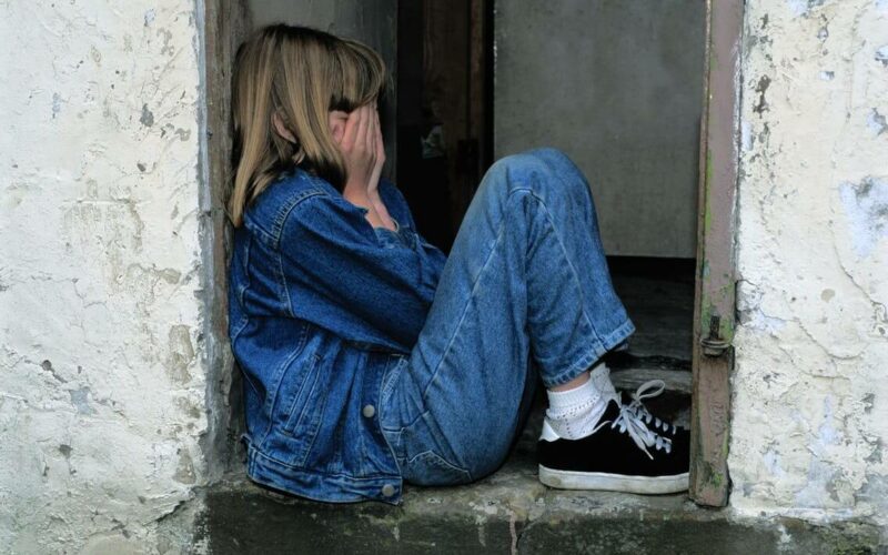 teenage girl sitting with head in hands