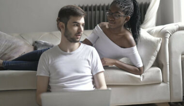 woman lying on bed with hand on boyfriend's head