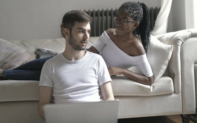 woman lying on bed with hand on boyfriend's head