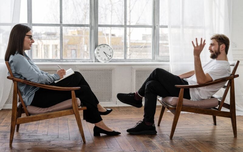 woman sitting with notepad speaking to man across from her