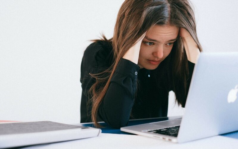 woman burying her head in computer looking stressed