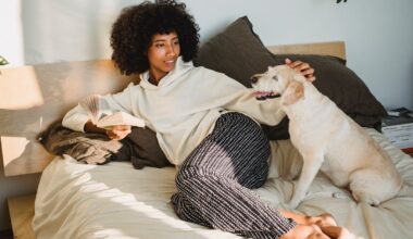 happy woman sitting on bed with book and dog