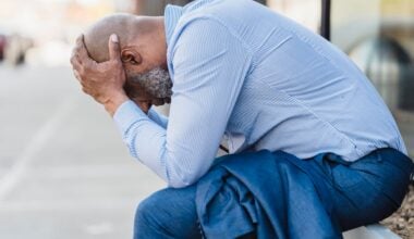 stressed man bent down holding head in hands