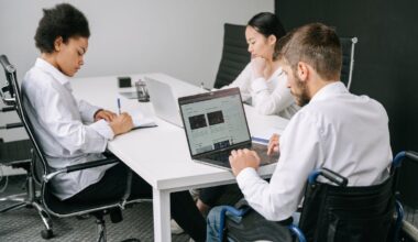 man in wheelchair sitting at desk with coworkers