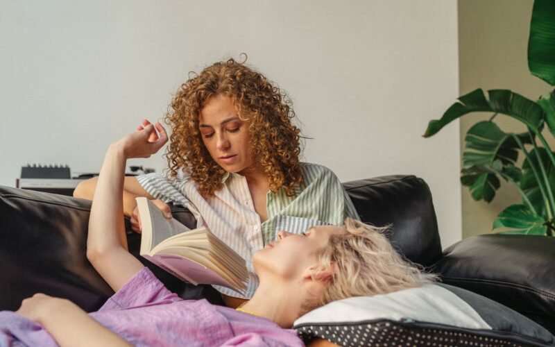 woman reading to femal friend on couch