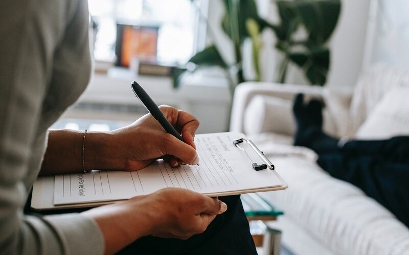 psychologist writing on clipboard during session