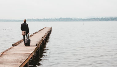 man walking down dock with suitcase