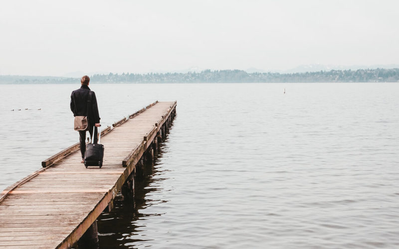 man walking down dock with suitcase