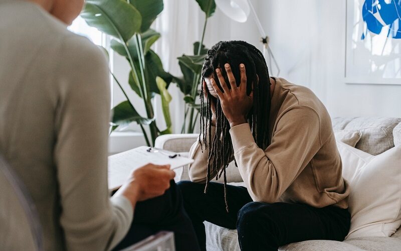 Stressed black man with dreadlocks talking to therapist