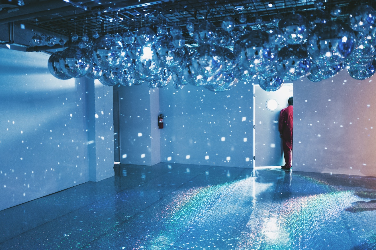 Man standing in doorway under disco balls